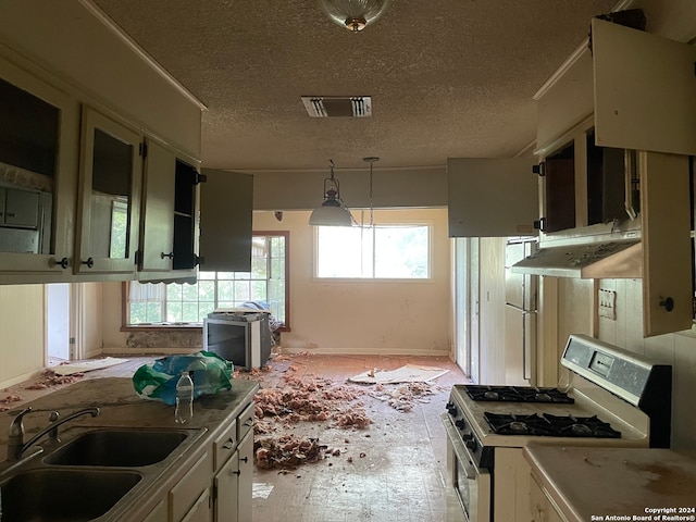 kitchen featuring sink, hanging light fixtures, white gas stove, and a textured ceiling