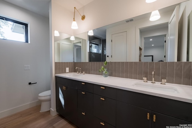 bathroom with hardwood / wood-style flooring, decorative backsplash, toilet, and vanity