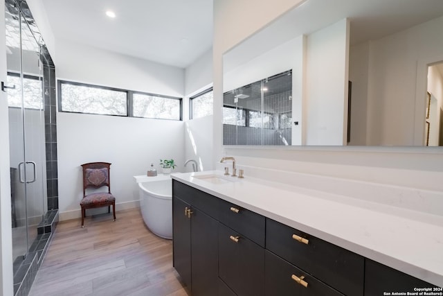 bathroom featuring hardwood / wood-style flooring, vanity, and separate shower and tub