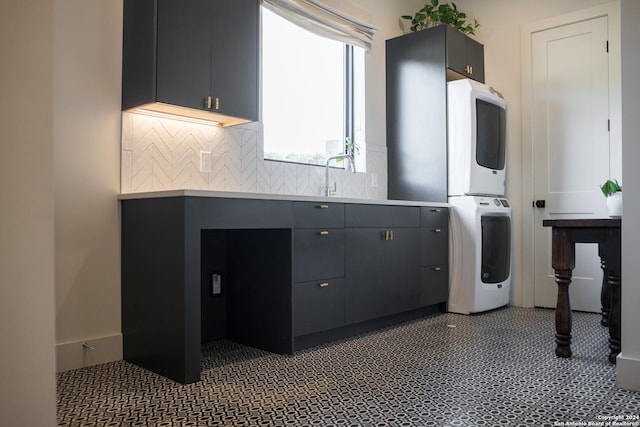 kitchen with tasteful backsplash, stacked washer / dryer, gray cabinetry, and sink