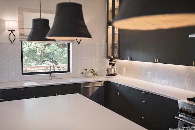 kitchen with pendant lighting, backsplash, appliances with stainless steel finishes, and sink