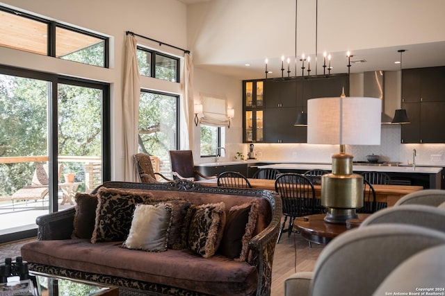 living room featuring a high ceiling, hardwood / wood-style flooring, an inviting chandelier, and sink