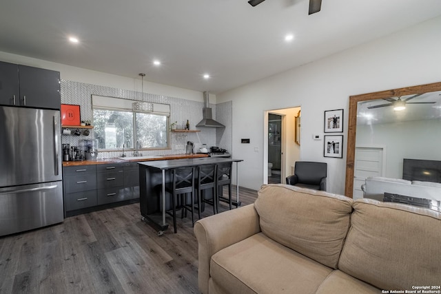 kitchen featuring a kitchen bar, backsplash, decorative light fixtures, dark hardwood / wood-style flooring, and stainless steel refrigerator