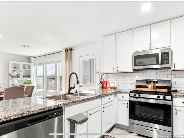 kitchen featuring light stone counters, appliances with stainless steel finishes, sink, and white cabinetry