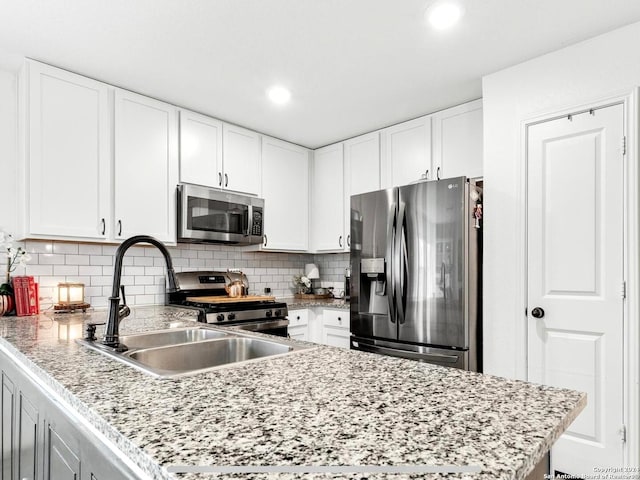 kitchen with appliances with stainless steel finishes, decorative backsplash, sink, and white cabinets