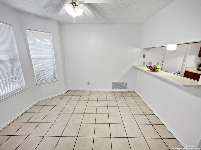 tiled spare room featuring a textured ceiling and ceiling fan