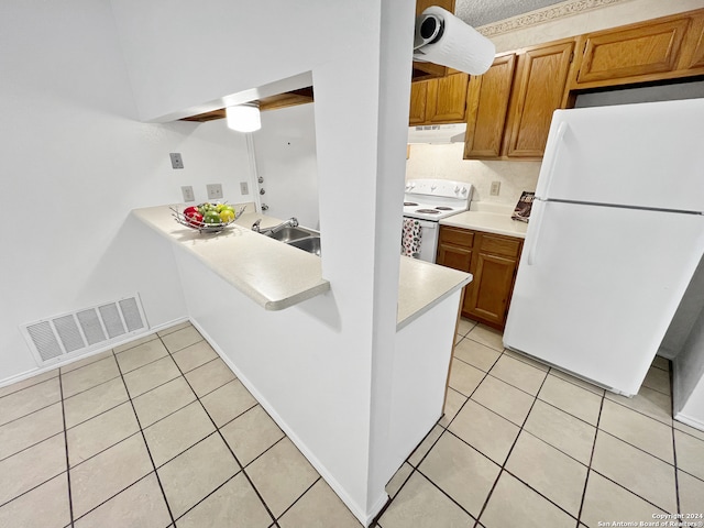 kitchen featuring white appliances, kitchen peninsula, light tile patterned floors, and sink