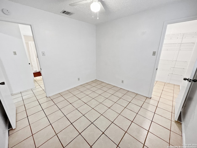 tiled empty room featuring ceiling fan and a textured ceiling