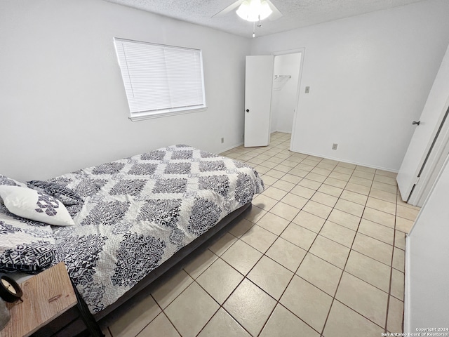 bedroom with a textured ceiling, light tile patterned floors, and ceiling fan