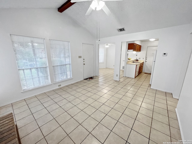 unfurnished room with lofted ceiling with beams, ceiling fan, light tile patterned flooring, and a healthy amount of sunlight