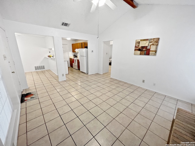 spare room with lofted ceiling with beams, ceiling fan, light tile patterned floors, and a textured ceiling