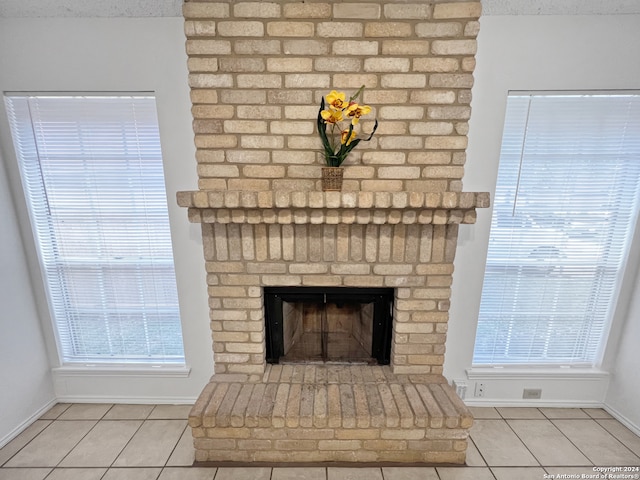 interior details featuring a brick fireplace, a textured ceiling, and tile patterned floors