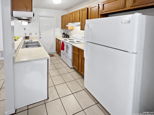 kitchen featuring a textured ceiling, sink, white appliances, and light tile patterned flooring