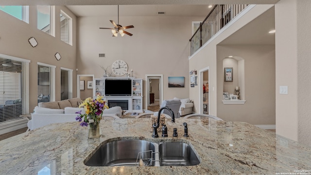 kitchen with light stone countertops, a high ceiling, sink, and ceiling fan