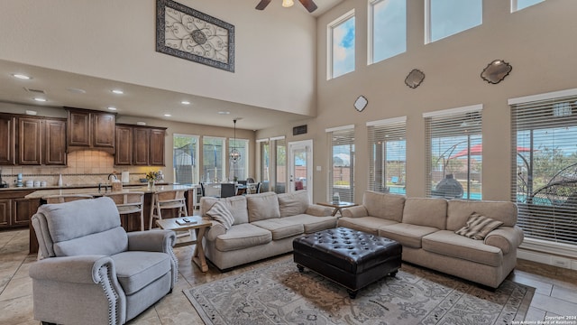 living room featuring ceiling fan, plenty of natural light, and a towering ceiling