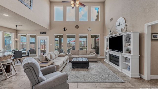 tiled living room with a textured ceiling, a high ceiling, ceiling fan, and plenty of natural light