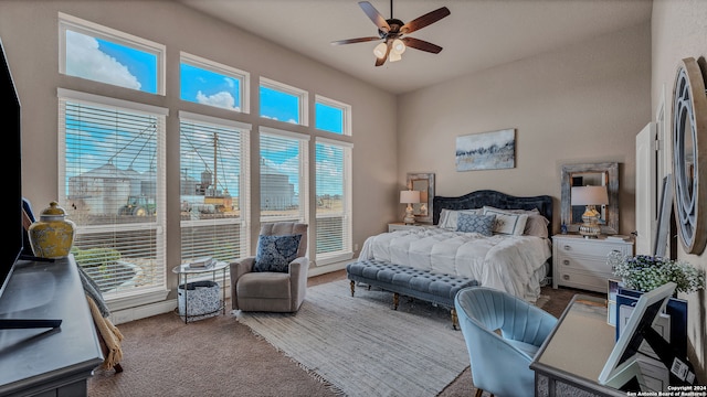 bedroom featuring ceiling fan, a high ceiling, and multiple windows