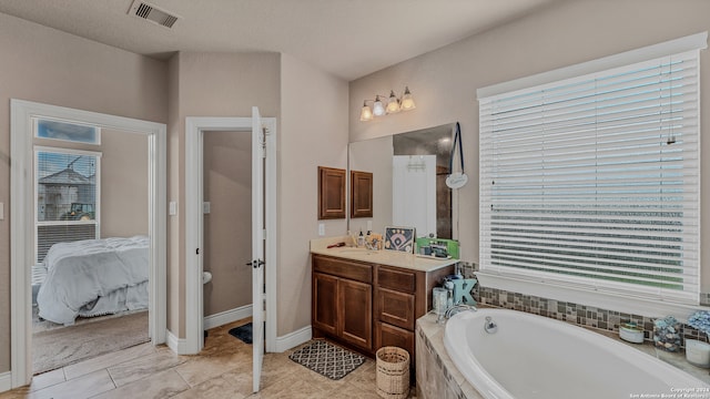 bathroom featuring a healthy amount of sunlight, vanity, and a relaxing tiled tub