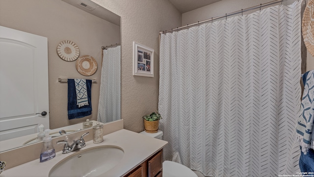 bathroom featuring curtained shower, vanity, and toilet