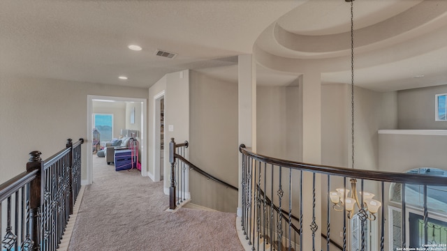 corridor featuring light carpet, a chandelier, and a raised ceiling