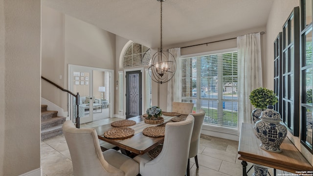 tiled dining area with a notable chandelier, a high ceiling, plenty of natural light, and french doors