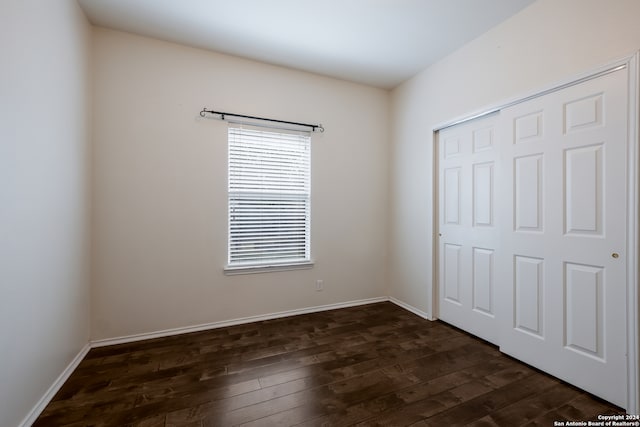 unfurnished bedroom with dark hardwood / wood-style flooring and a closet