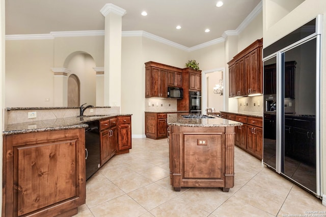 kitchen featuring light stone countertops, black appliances, a center island, and tasteful backsplash