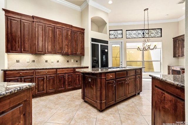 kitchen with light stone counters, black built in fridge, hanging light fixtures, an inviting chandelier, and ornamental molding