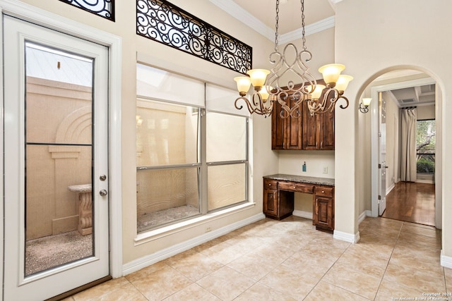 interior space with baseboards, ornamental molding, a chandelier, tile patterned floors, and a high ceiling