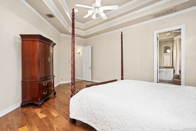 bedroom featuring ceiling fan, ornamental molding, hardwood / wood-style flooring, a tray ceiling, and ensuite bathroom