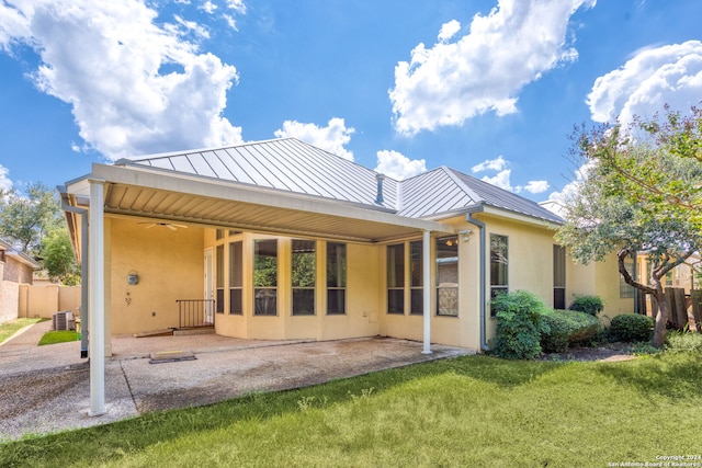 back of property featuring a yard, metal roof, a standing seam roof, and stucco siding