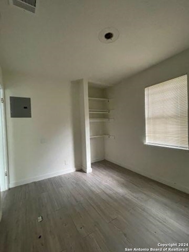 empty room featuring electric panel and hardwood / wood-style flooring