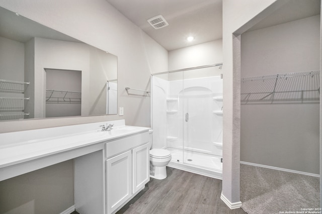 bathroom featuring hardwood / wood-style floors, a shower with door, vanity, and toilet