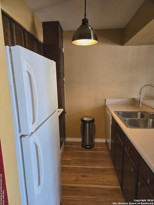 kitchen with white appliances, decorative light fixtures, dark brown cabinetry, dark hardwood / wood-style floors, and sink