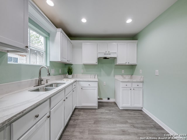 kitchen featuring white cabinets, light hardwood / wood-style floors, and sink