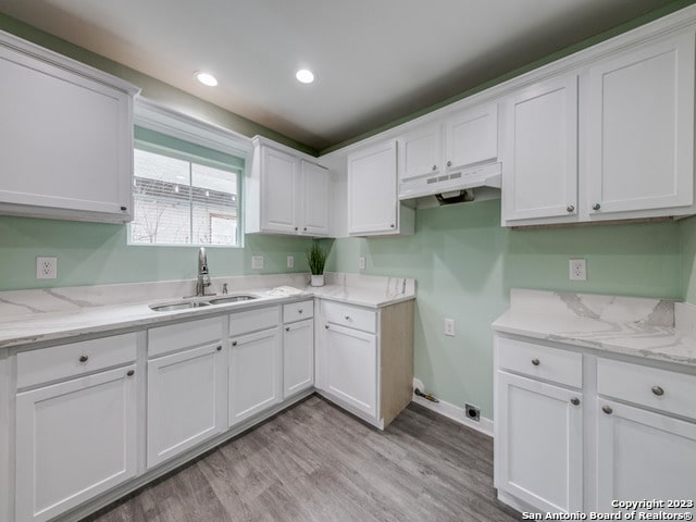 kitchen featuring white cabinets, light wood-type flooring, and sink