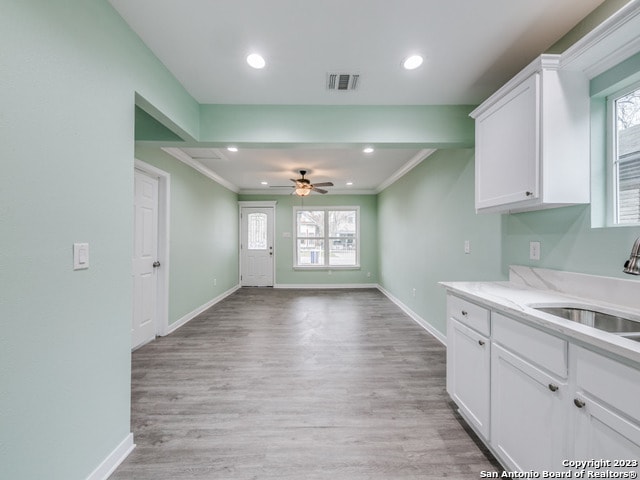 kitchen featuring sink, white cabinets, light hardwood / wood-style flooring, crown molding, and ceiling fan