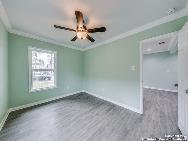 spare room with light wood-type flooring, ornamental molding, and ceiling fan