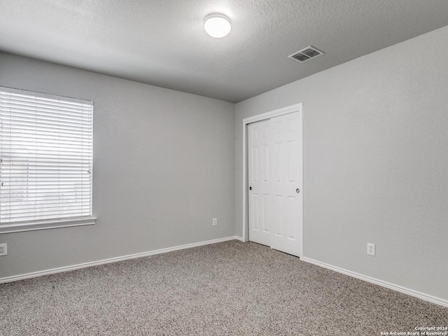 unfurnished room featuring a textured ceiling and carpet flooring