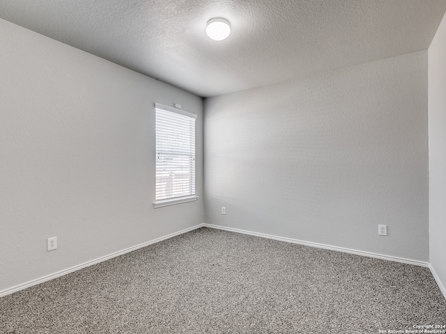 carpeted empty room featuring a textured ceiling