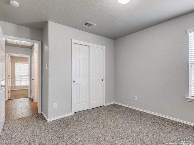 unfurnished bedroom featuring a textured ceiling, carpet flooring, and a closet