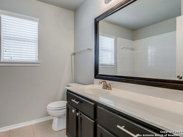 bathroom featuring a tile shower, tile patterned flooring, vanity, and toilet