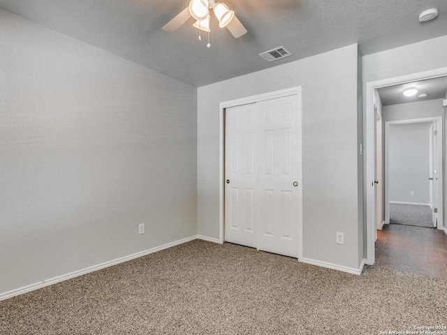 unfurnished bedroom featuring a closet, ceiling fan, carpet floors, and a textured ceiling