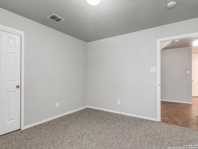 unfurnished room with a textured ceiling and carpet flooring