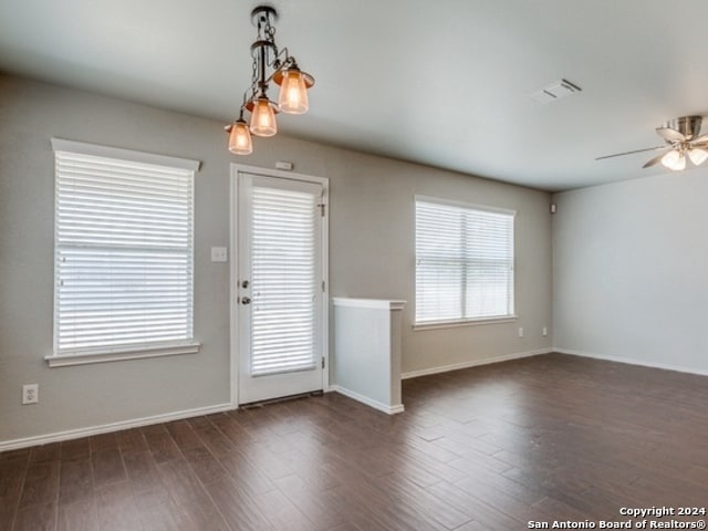 interior space with ceiling fan with notable chandelier and dark wood-type flooring