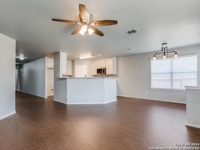 unfurnished living room featuring ceiling fan and dark wood-type flooring