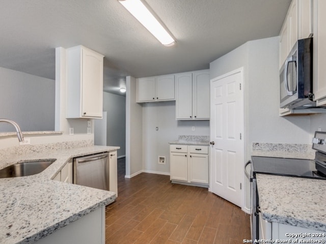 kitchen with light stone counters, white cabinets, sink, light hardwood / wood-style flooring, and appliances with stainless steel finishes