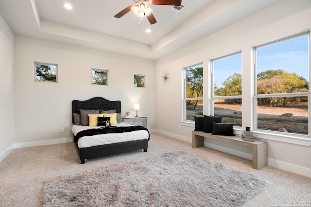 carpeted bedroom featuring ceiling fan and a raised ceiling