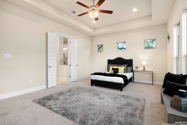 bedroom featuring ceiling fan, connected bathroom, carpet, and a raised ceiling