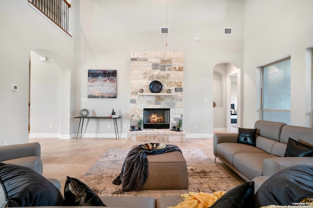 tiled living room with a fireplace and a towering ceiling